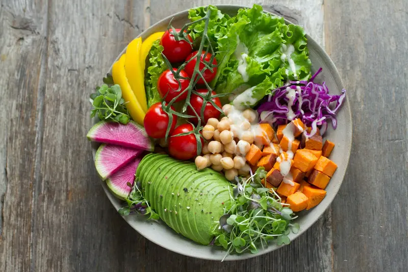 Bowl of salad with avocado, chickpeas, tomatoes and sweet potato