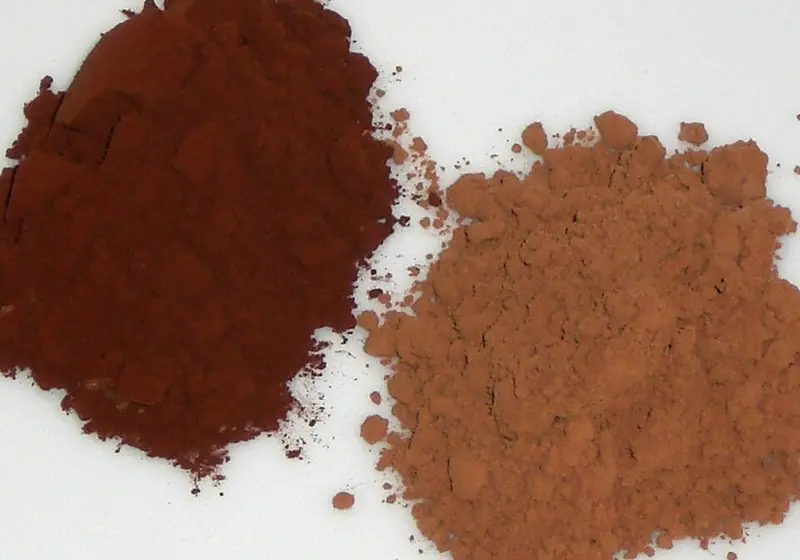 Two piles of cocoa powder side by side, dark Dutch-processed and lighter natural cocoa