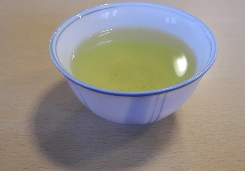 White cup of green tea on a wooden table