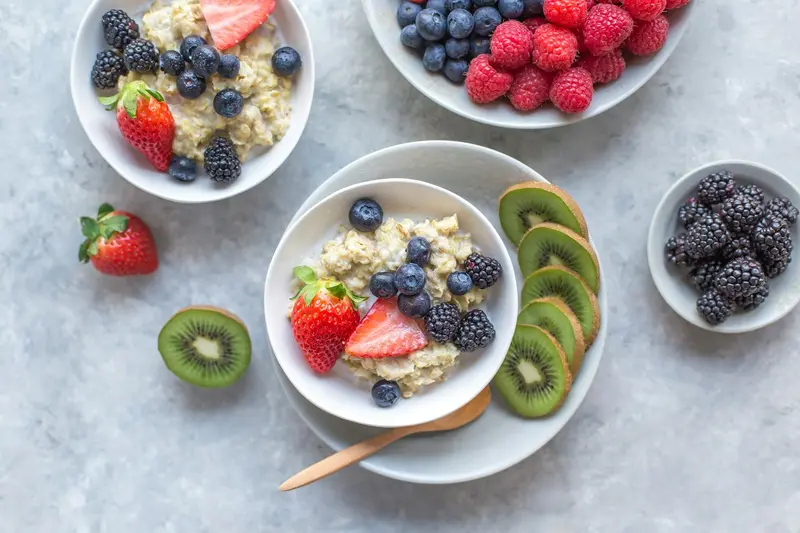 Bowls of oats topped with blueberries, strawberries and kiwi