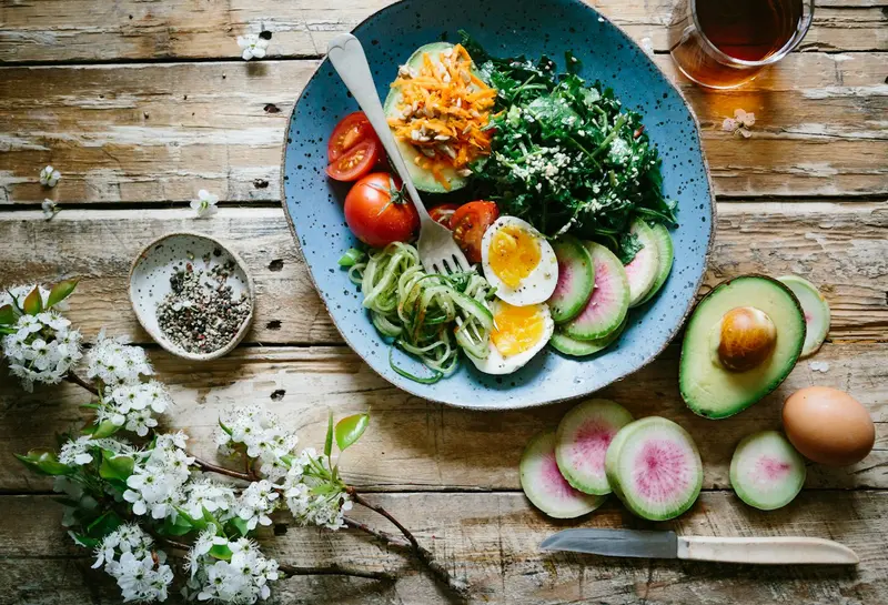 Breakfast plate with eggs, avocado, greens and fresh vegetables