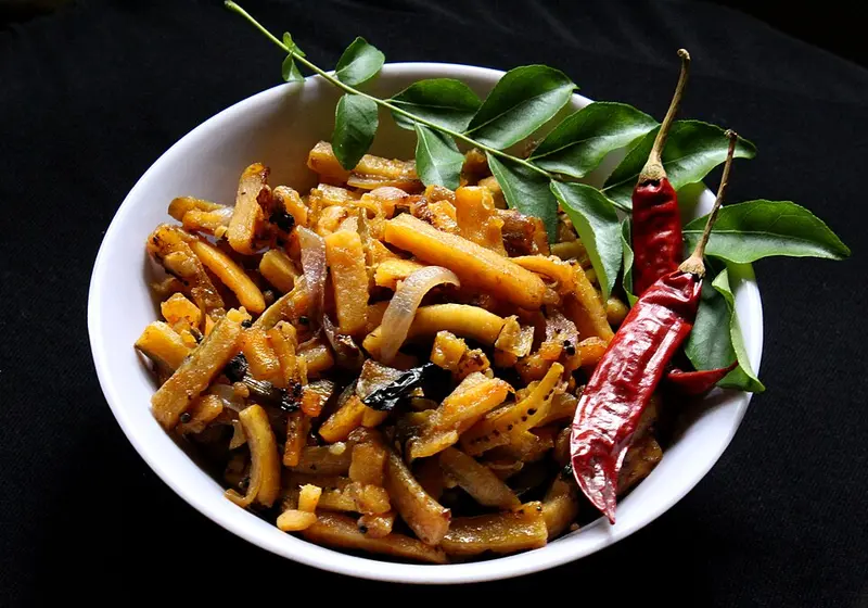Bowl of South Indian raw banana fry with curry leaves and dried red chillies