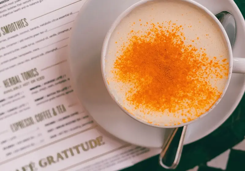 Turmeric latte in a white cup dusted with turmeric