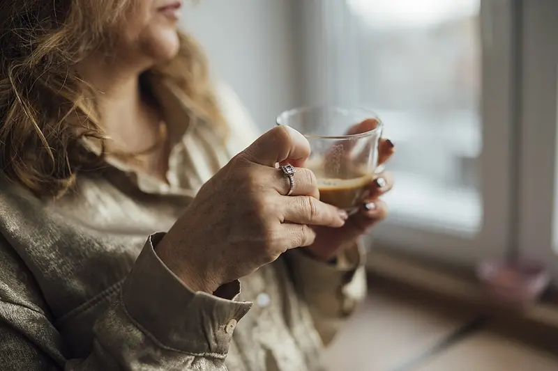 Woman holding a warm drink by a sunny window